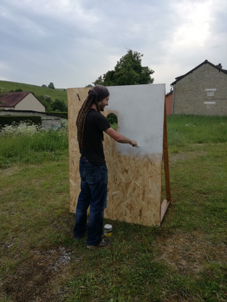 Membre de l'équipe du Projet CarTylion en train d'appliquer de la peinture blanche sur un passe-tête