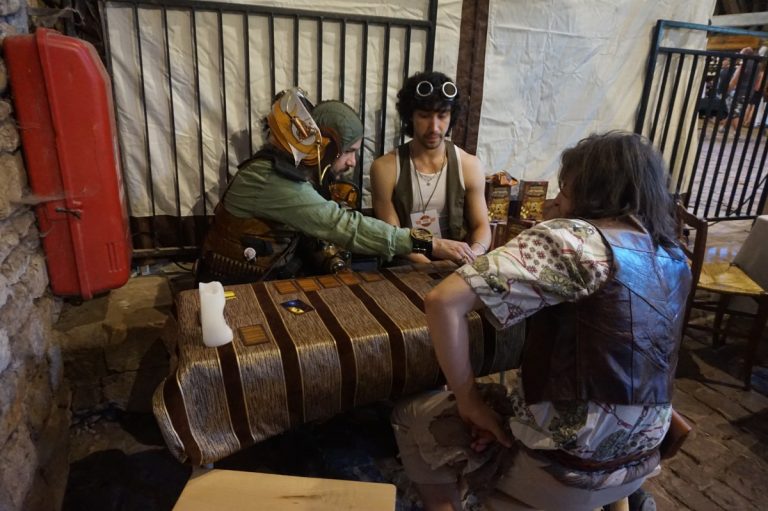 Personnes déguisées assises autour d’une table pour jouer à un jeu.