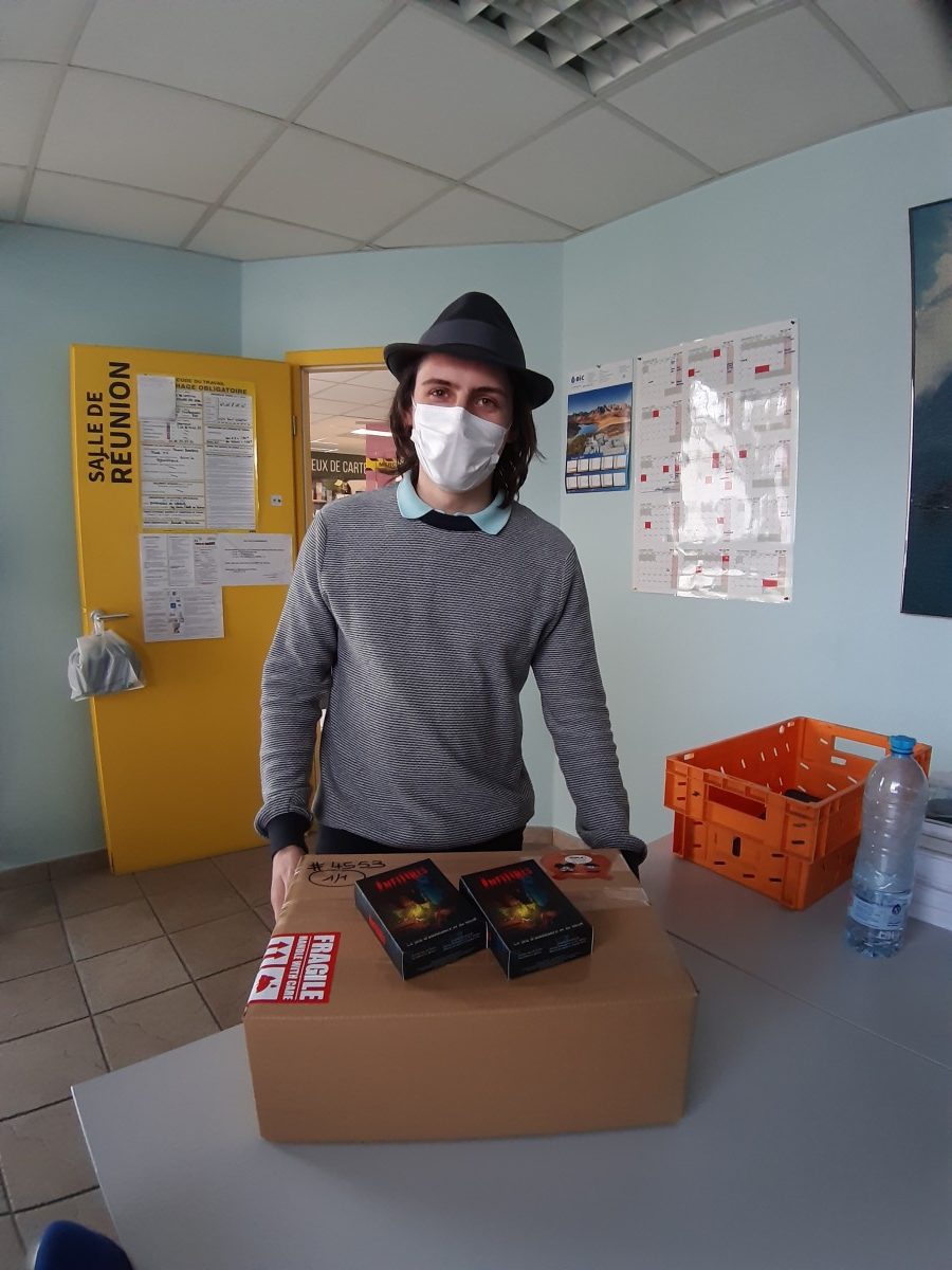 Florian avec un carton de jeux Infiltrés, et deux exemplaires présentés en dehors du carton